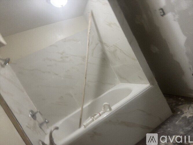 A white bathtub with a shower head and a hose attached to it.