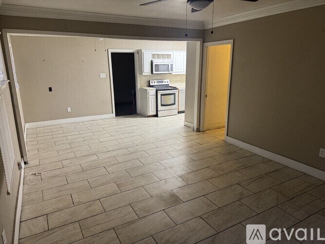 A spacious room with a kitchenette and a door leading to a balcony.