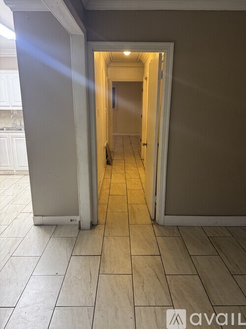 A hallway with tiled flooring and a doorway leading to another room.