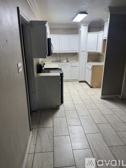 A kitchen with white cabinets and a tile floor.