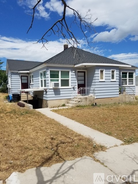 A small house with a grey roof and a white fence.
