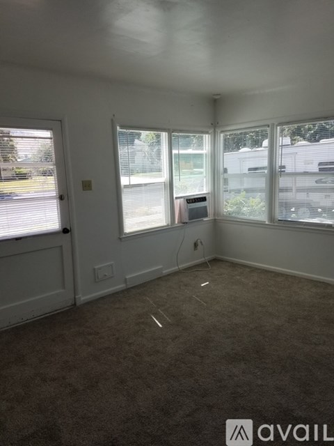 A room with carpeted floor and a window overlooking a parking lot.