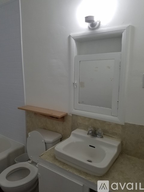 A bathroom with a toilet, sink and mirror.