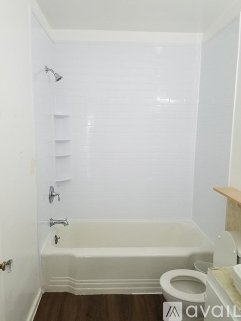 A white bathroom with a tub, toilet and sink.