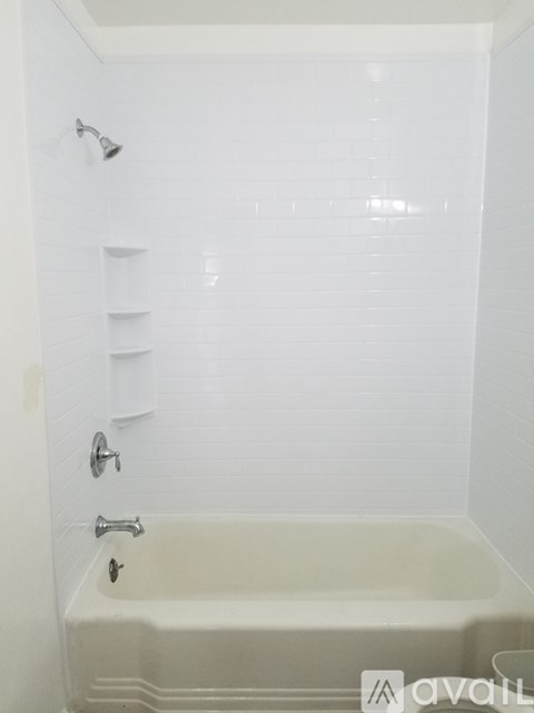 A white bathroom with a white tub and shower.