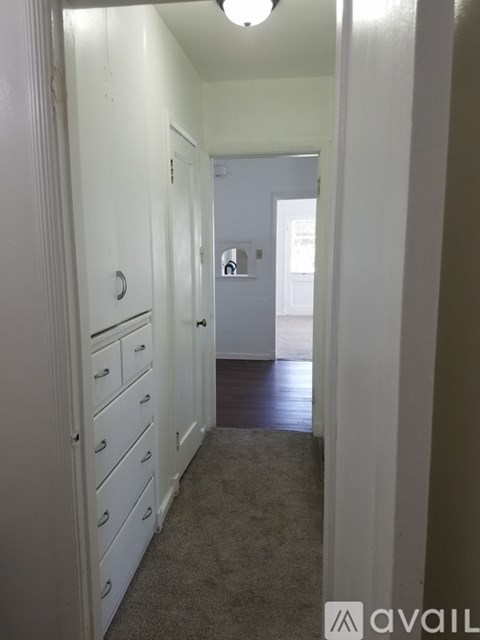 A hallway with a carpeted floor and white walls.