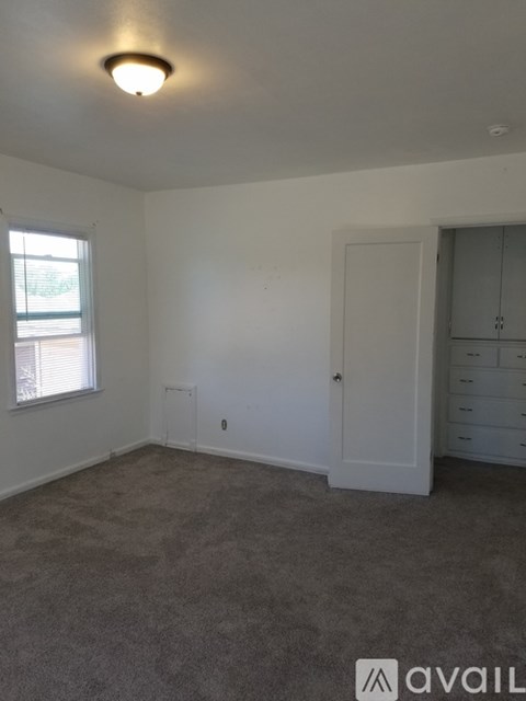 A room with a carpeted floor and a window with blinds.