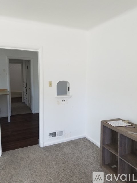 A room with a white wall and a small shelf.