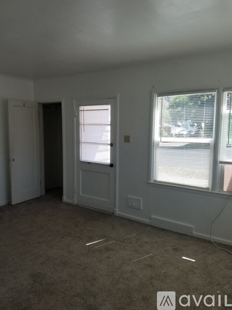 A room with a carpeted floor and a window with blinds.