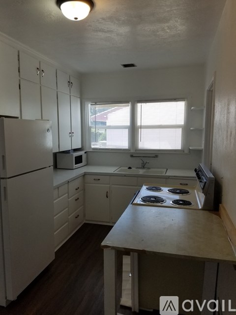 A kitchen with white cabinets and a stove top oven.