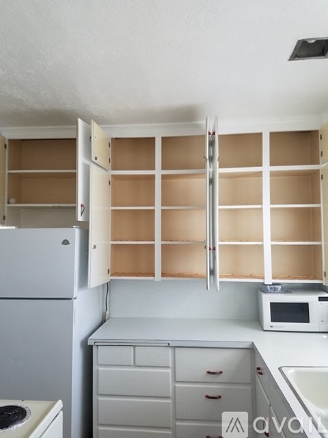 A kitchen with a white refrigerator, microwave, and cabinets.