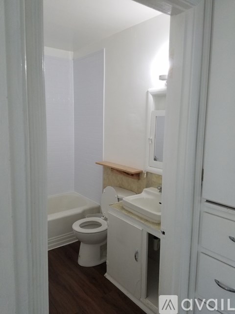 A white bathroom with a toilet, sink, and cabinet.