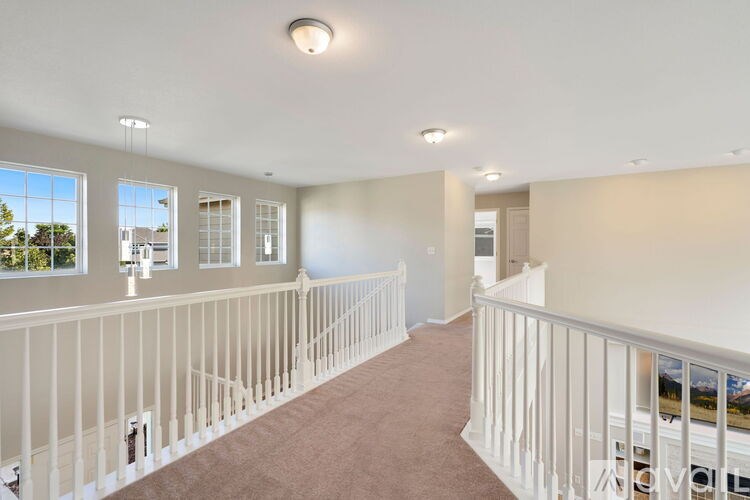 A well-lit, empty room with a carpeted floor and white railings.