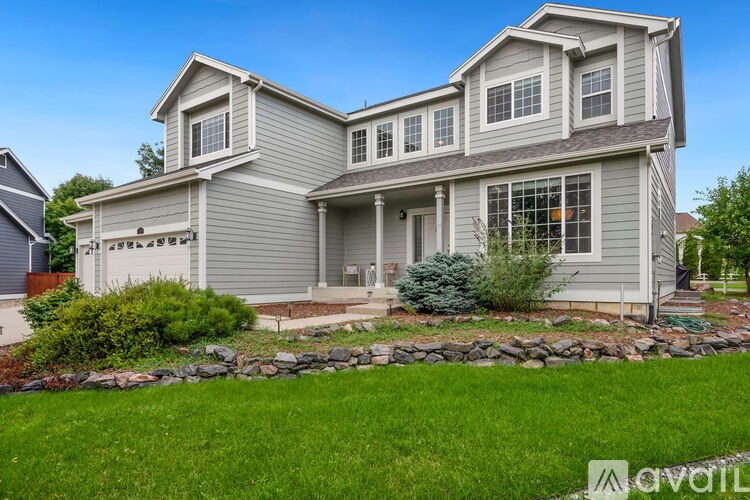 A house with a grey exterior and a stone wall in front.