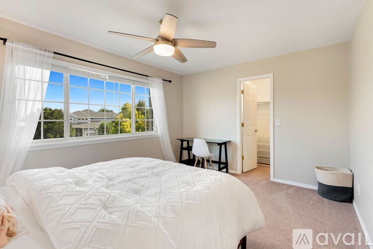 A bedroom with a large bed and a window overlooking a residential area.