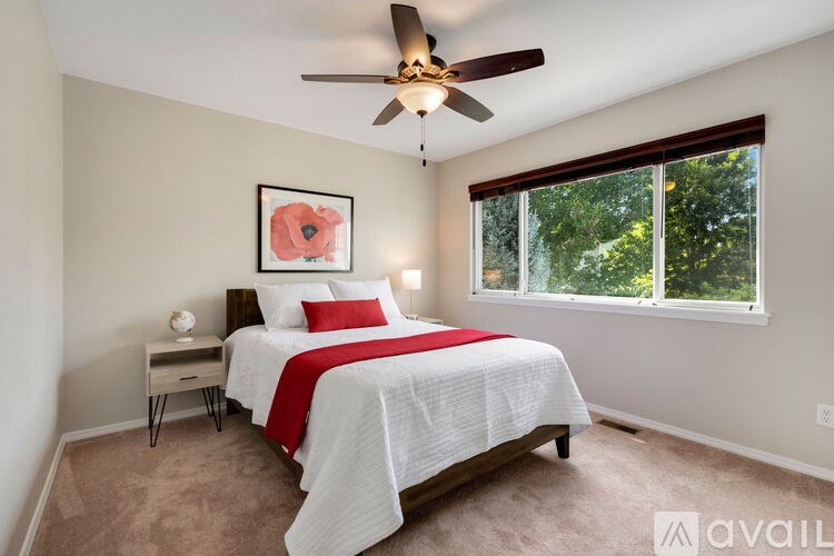 A bedroom with a bed, a ceiling fan, and a window.