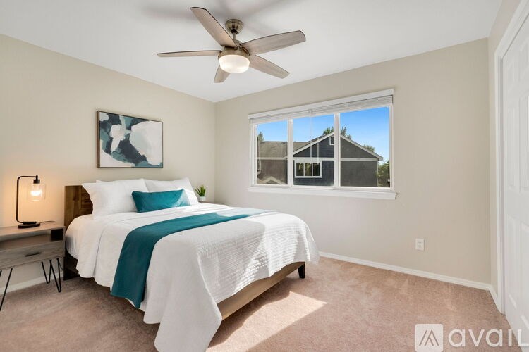 A bedroom with a bed, a ceiling fan, and a window.