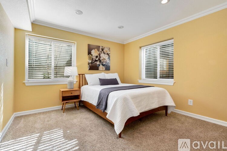 A bedroom with a bed, nightstand, and window with blinds.