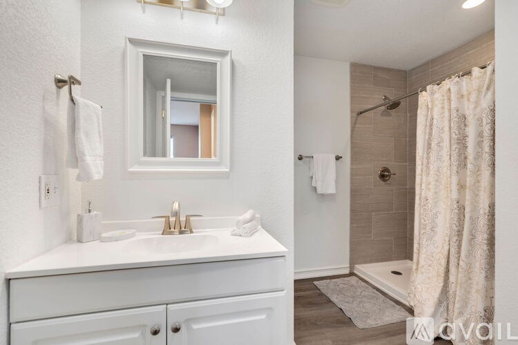 A white bathroom with a sink, mirror, and shower.