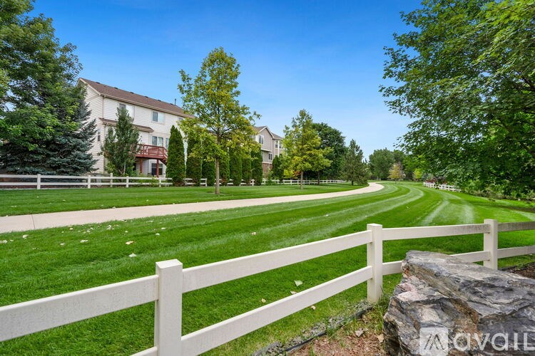 A white picket fence borders a well-manicured lawn in front of a large building.