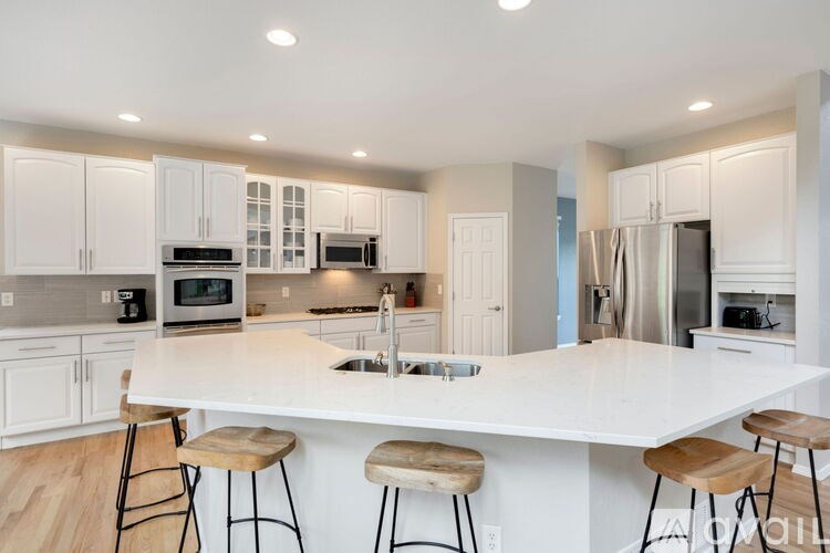 A kitchen with white cabinets and a large island with bar stools.
