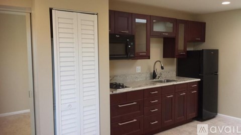 A kitchen with brown cabinets and a black refrigerator.