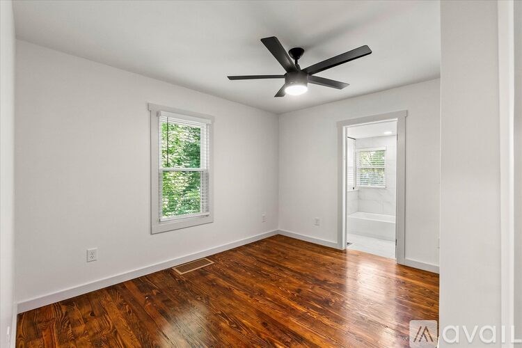 A room with a ceiling fan and wooden floors.