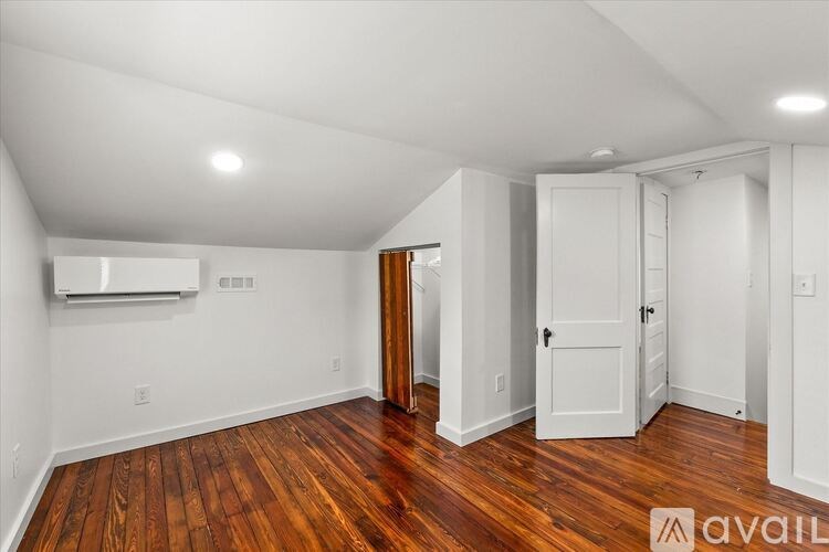 A room with wooden floors and white walls, with a door on the right side.