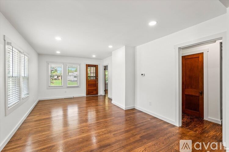 A spacious room with wooden floors and white walls.