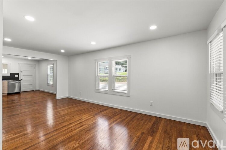 A spacious room with wooden floors and white walls.
