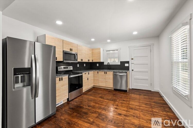 A modern kitchen with wooden floors and stainless steel appliances.