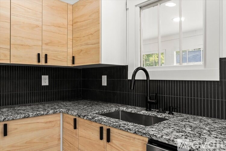 A kitchen with a black counter top and wooden cabinets.