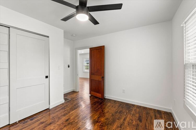 A room with a ceiling fan and wooden floors.