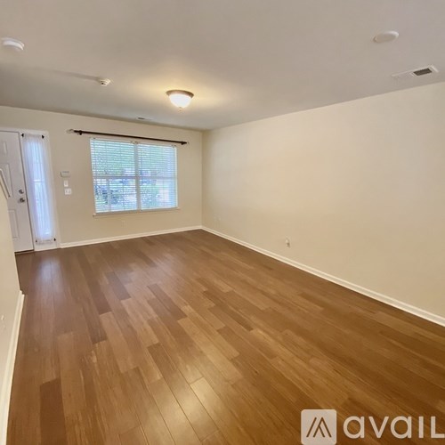 A room with wooden flooring and a window with blinds.