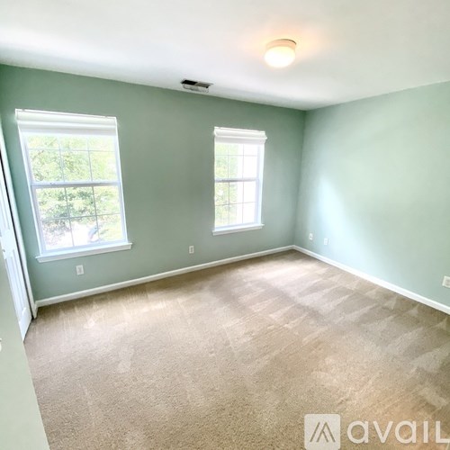 A room with two windows and carpeted floor.