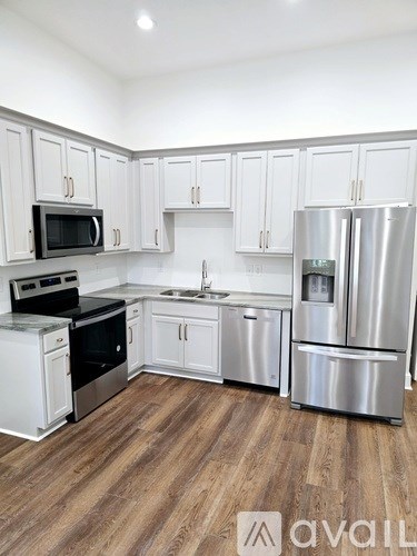 A kitchen with white cabinets and a wooden floor.