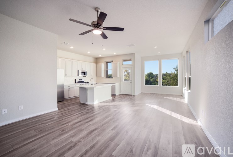 A spacious room with a ceiling fan and wooden flooring.