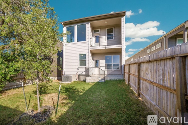 A sunny day at a two-story apartment building with a green lawn and a wooden fence.