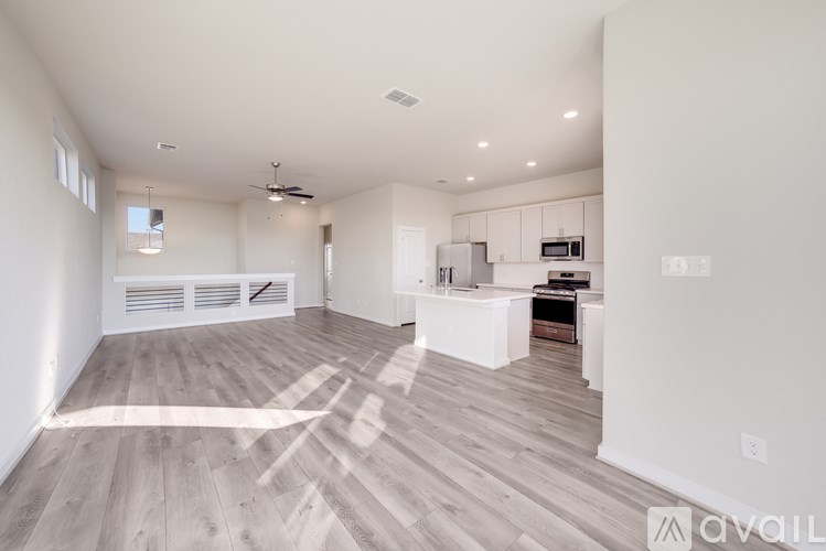 A spacious kitchen with white cabinets and a wooden floor.