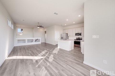 A spacious kitchen with white cabinets and a wooden floor.
