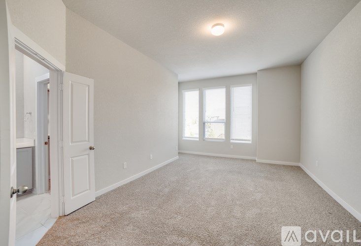 A room with a carpeted floor and a window with blinds.