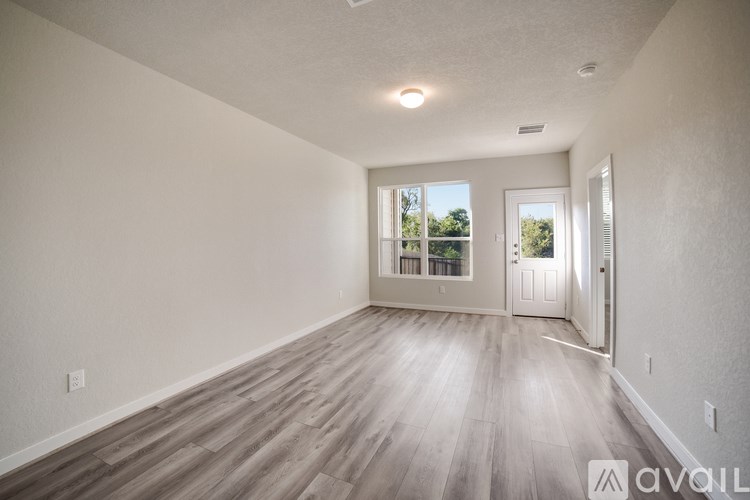 A spacious room with wooden flooring and white walls.