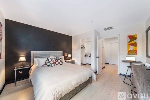 A bedroom with a large bed and a desk with a laptop.