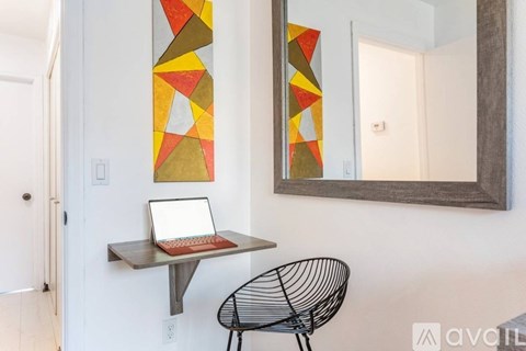 A laptop is on a desk under a mirror with a geometric design.