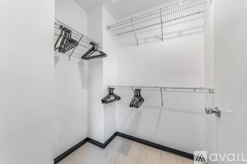 A white wall with a metal rack holding clothes.