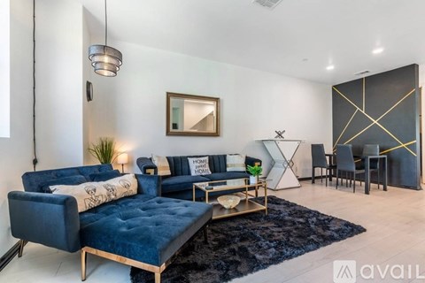 A living room with a blue velvet sofa and a black and white rug.