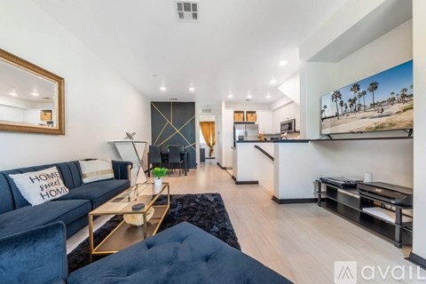A living room with a black couch and a television on the wall.