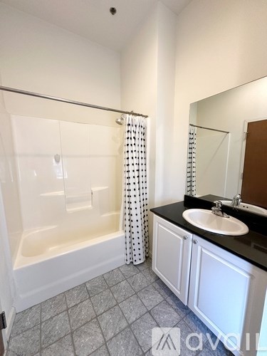 A white bathroom with a black counter top and a white bathtub.