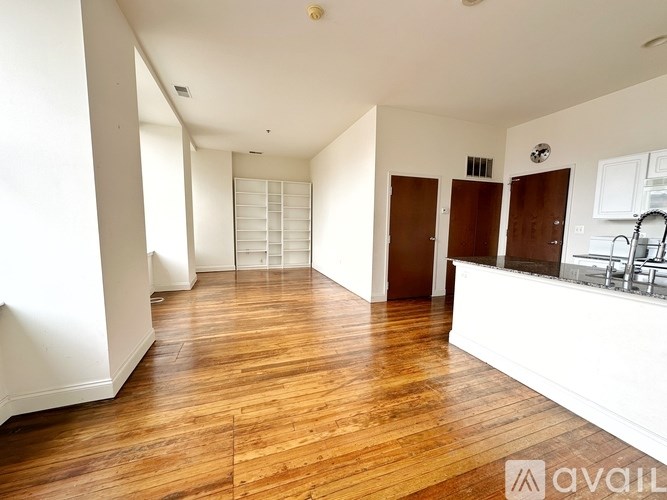 A spacious room with wooden floors and white walls.