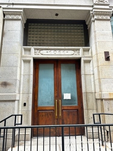 A brown door with a glass panel and a sign on it.